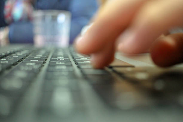 boy is pressing the keys of a laptop to find information for school