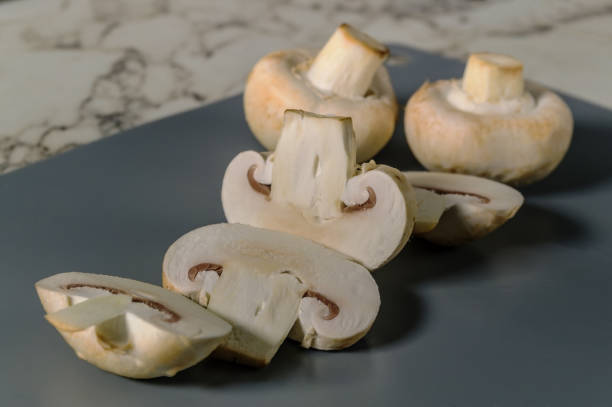 A close up of sliced mushrooms on a counter. The mushrooms are cut in half and arranged in a row