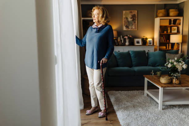 istock Senior woman standing by a window with a cane 2088466604