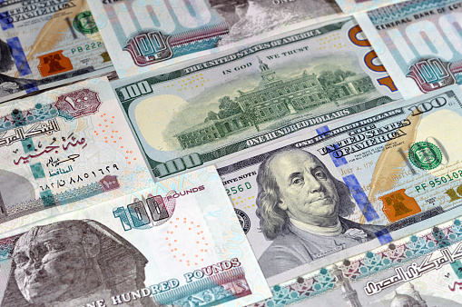 Egyptian money banknotes of 100 EGP LE one hundred pounds bill and USD American cash of 100 dollars, money exchange rates of Egypt and United states of America, inflation and economy concept, selective focus