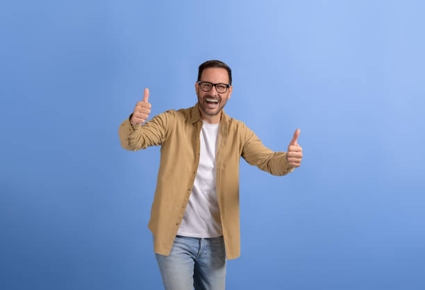 istock Successful young businessman showing thumbs up signs ecstatically while posing on blue background 2088473856