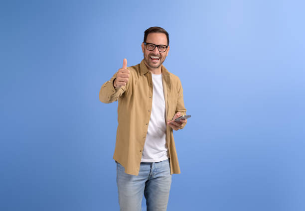 istock Confident happy freelancer texting over smart phone and showing thumbs up gesture on blue background 2088474377