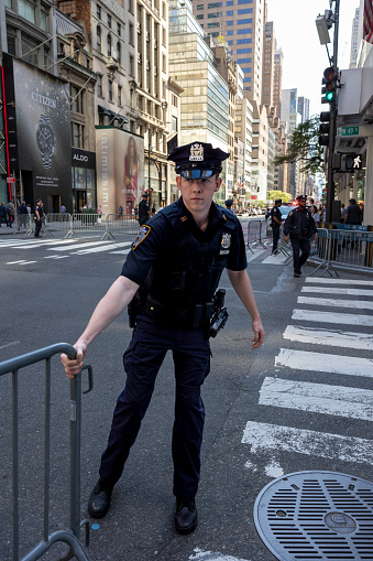 Manhattan, New York, USA - September 20, 2023: A uniformed NYPD officer drags a crowd barrier to cordon off an intersection on 5th Avenue for the passage of the presidential motorcade