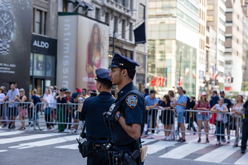 Manhattan, New York, USA - September 20, 2023: NYPD officers in uniform at an intersection on 5th Avenue during the passage of the presidential motorcade. Public is behind crowd barriers.