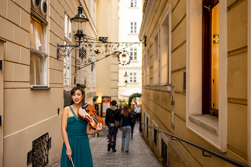 Young woman violinist standing on the street in Vienna.