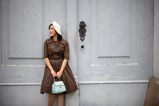 Fashionable young woman standing by a big wooden door on the street in Vienna.