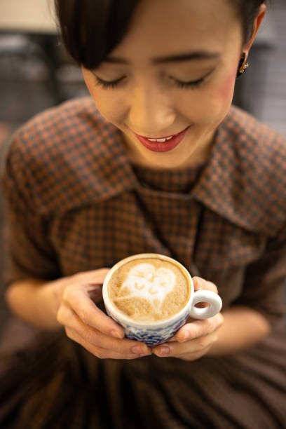 Modern young woman looking at espresso froth art in cafe.