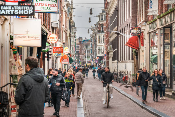 Amsterdam, Netherlands, March 13, 2024. City center at noon. Crowded street with shops and restaurants.