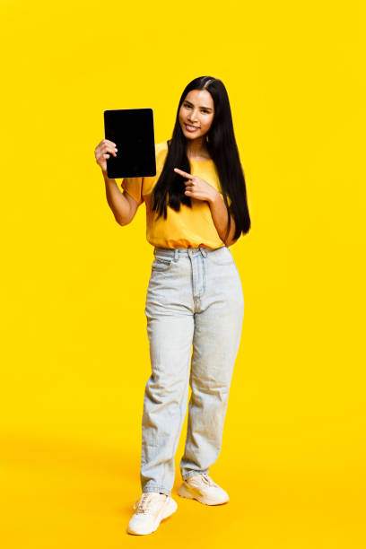 istock Young woman presenting tablet on yellow background 2088591468
