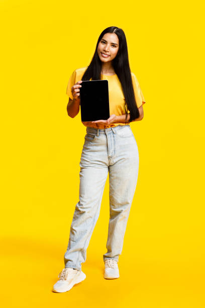 istock Confident woman holding tablet on yellow background 2088591470