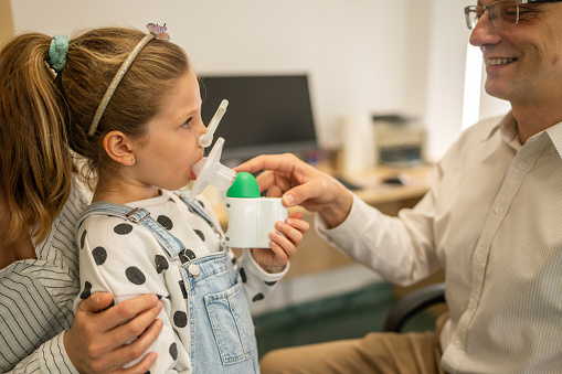Close-up shot of little girl taking spirometry test in medical clinic