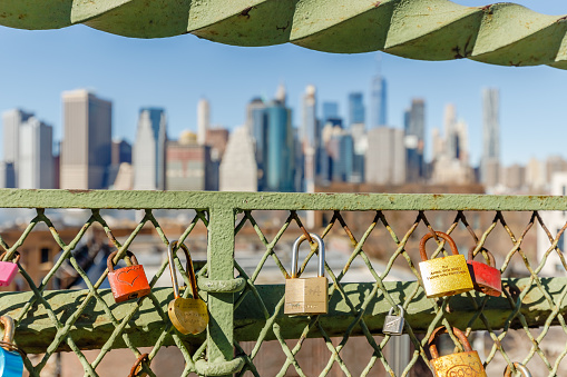 Brooklyn Queens, New York City, USA - February 11, 2023: love padlock hanging on a fence in front of manhattan on a winter day