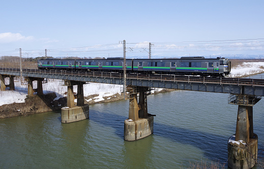 Ebetsu-city, Hokkaido, Japan - March 16, 2024 : KIHA 201 Local train crossing the Yubari River Bridge