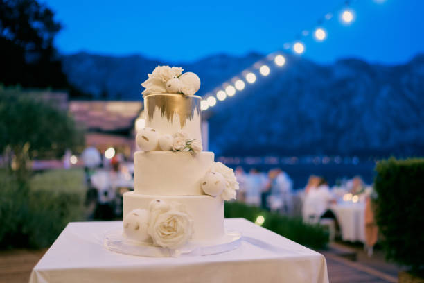 istock Three-tier wedding cake stands on a table in an evening garden with illumination 2088833050
