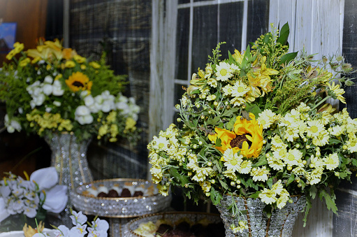 Vases with flowers in yellow and white tones decorating a golden wedding party table