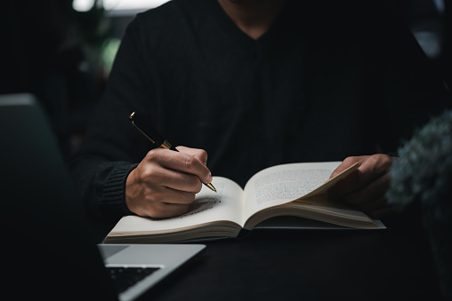 man hands with pen writing on notebook in the office.learning, education and work.writes goals, plans, make to do and wish list on desk.