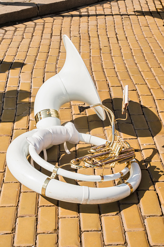 White fiberglass sousaphone on town street ceramic pavers closeup