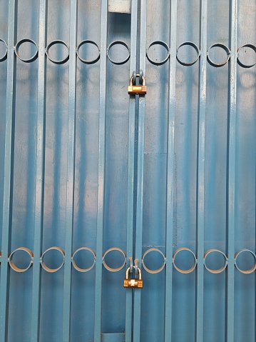 Two padlocks locking  a blue metal door