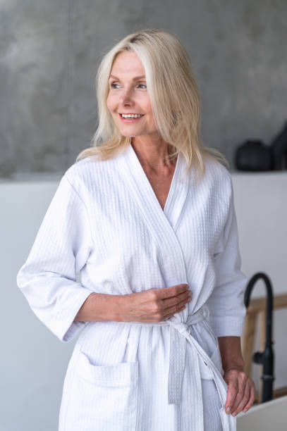 istock Female standing in bathroom, tie a robe, smiling wide 2088875875