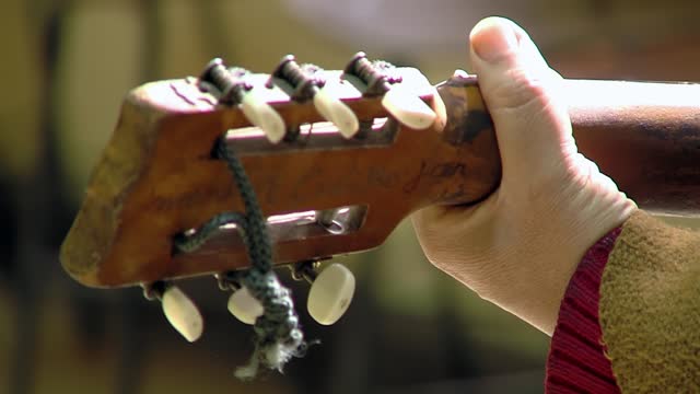 A Man playing A Classical Guitar with Inscriptions on the Back of the Headstock. Close Up.