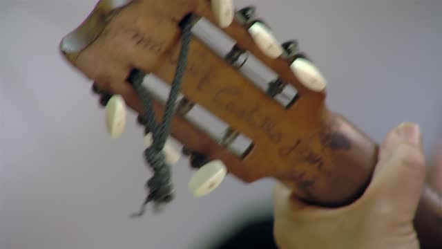 A Man playing A Classical Guitar with Inscriptions on the Back of the Headstock. Close Up.