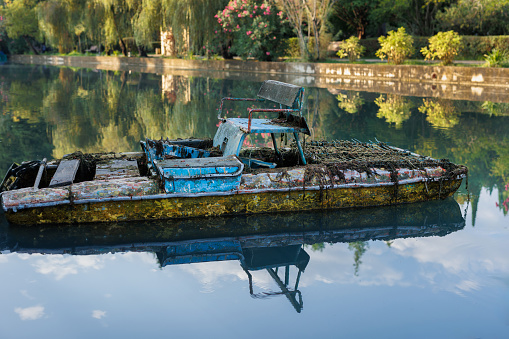 An old rusty catamaran is standing by the river bank