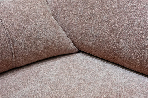 The angle between the seat, back and armrest on the sofa. Cushioned furniture. Close-up. Brown upholstery color. Currency plan. Background. Texture.