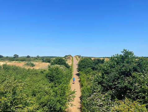 Jogger coming off a bridge on Marriott's Way, a disused railway track,  in Norfolk. July 2023