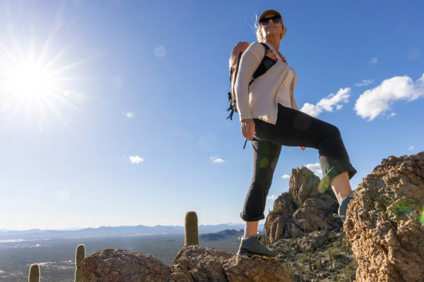 Mature woman ascends rock ridge crest