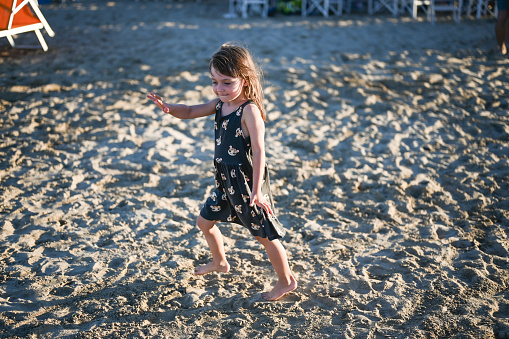 Little girl playing on a sandy beach.