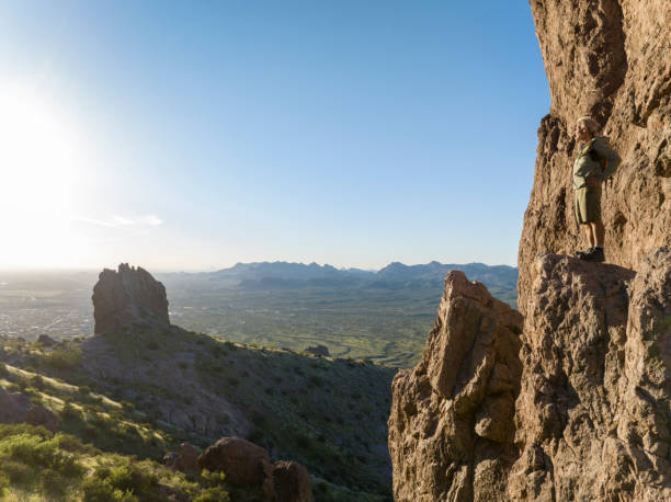 istock Hiker stands on rock pinnacle above desert 2088946113