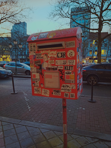 Brussels, Belgium. March 15 2024. Big red box. There are a lot of unusual stickers on the red box. Street decor right in the middle of the street. Evening Brussels