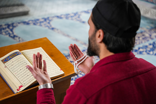 Muslim young man reading Quran praying in mosque