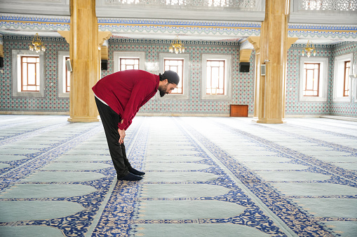 Muslim young man praying in the mosque