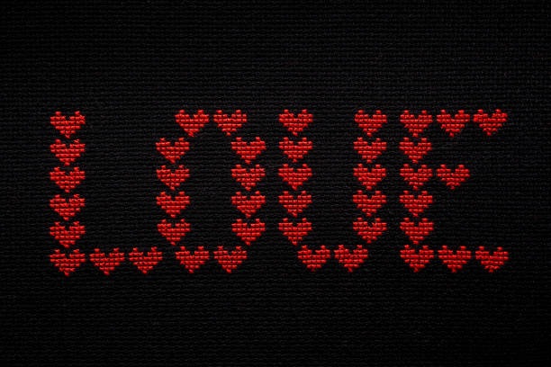 The word love is embroidered with red threads on black fabric.
