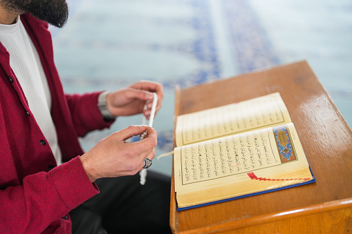 Muslim young man reading Quran praying in mosque