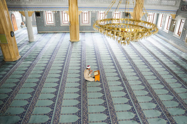 young male imam reading the quran in the mosque during ramadan. - glorification photos et images de collection