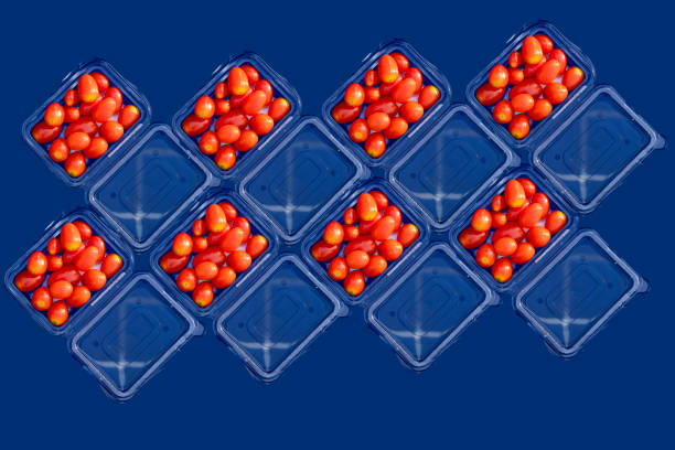 Close-up of fresh red cherry tomatoes neatly arranged in a clear plastic container, displayed against a clean white background, representing freshness, packaging, and healthy eating.