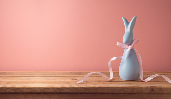 Easter holiday concept  with modern bunny on wooden table over pink background