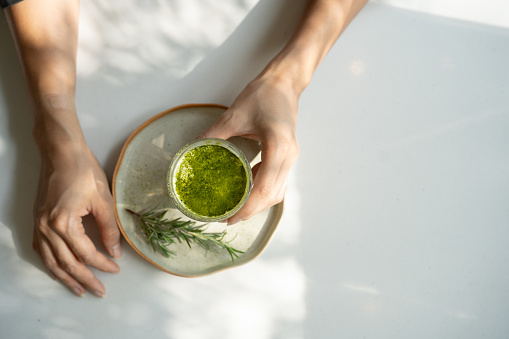 Morning Zen: Top View of Woman's Hand Holding Hot Matcha Green Tea, Embracing Japanese Wellness Ritual.