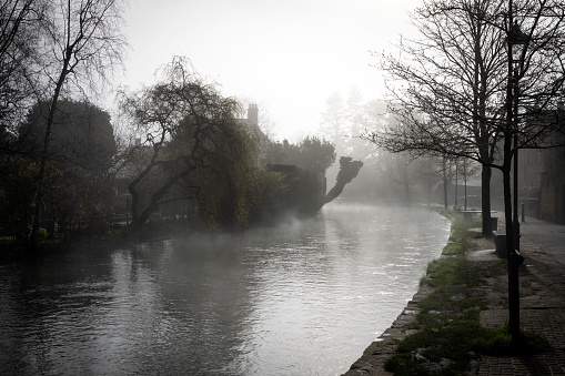 Bourton on the Water on a misty spring morning. This image captures the enchanting atmosphere as the village awakens. \n\nThe mist was hovering over the River Windrush and the charming stone bridges, adding a layer of tranquillity to this picturesque Cotswolds village, renowned for its scenic beauty and peaceful waterside setting.