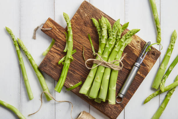 istock Peeling fresh green asparagus on wooden cutting board 2089042199