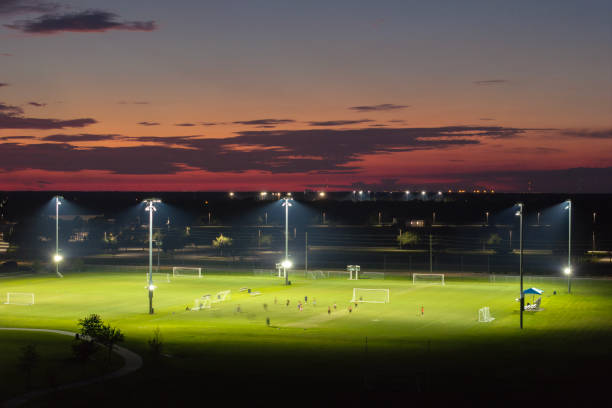 Aerial view of public sports park with people engaged in football game on grass stadium at sunset. Active way of life concept Aerial view of public sports park with people engaged in football game on grass stadium at sunset. Active way of life concept. high school soccer stock pictures, royalty-free photos & images