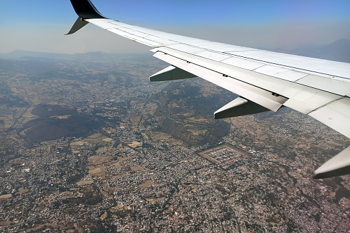 View on Mexico city through airplane window of commercial jet plane landing in local airport. Air travelling concept.