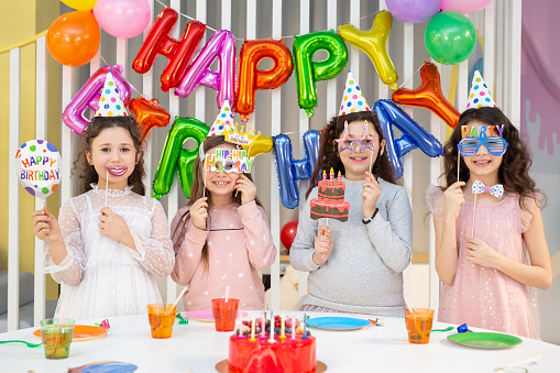 Happy children with photo booth props at birthday party