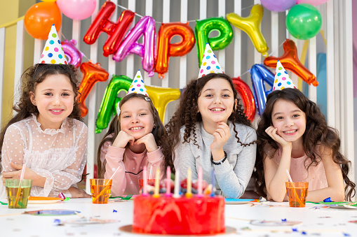 A festive cake with the number one on the background of a festive pink wall with gifts and flags in a serpentine. The concept of the holiday, birthday, anniversary. Sweet dessert for children