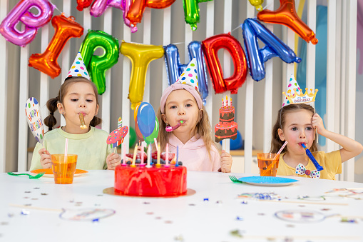 Group of children with pipes, funny inscriptions and masks are having fun at a birthday party