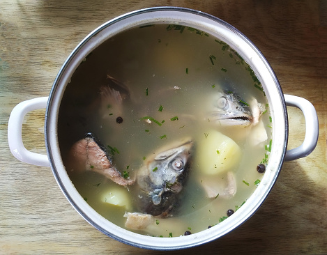 Fish soup in a pot, top view.