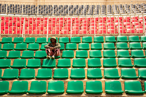 A young black woman sitting in a row of seats in an empty arena