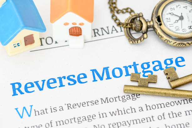 istock Model houses on a reverse mortgage document. A reverse mortgage is a loan for homeowners, converting home equity into cash. Repayment is typically deferred until the owner moves out or passes away. 2089127130